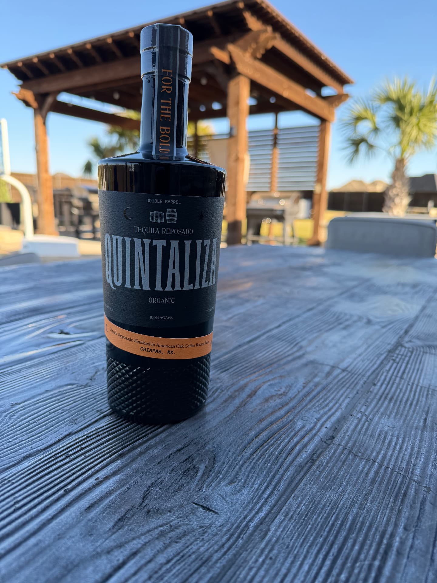Quintaliza organic tequila bottle photographed in a Texas outdoor setting